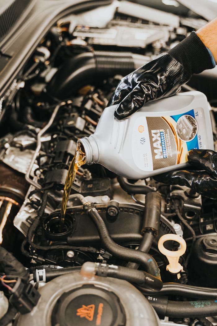 digital Close-up of mechanic pouring engine oil into car engine with gloved hands, showcasing automotive maintenance.
