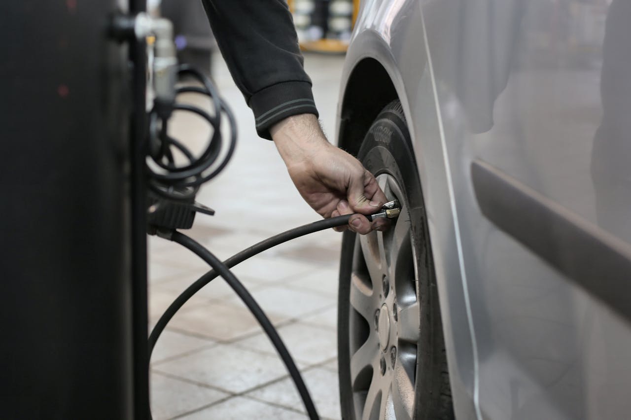 mobile-01 Mechanic inflating a car tire inside an auto repair shop, ensuring optimal tire pressure.