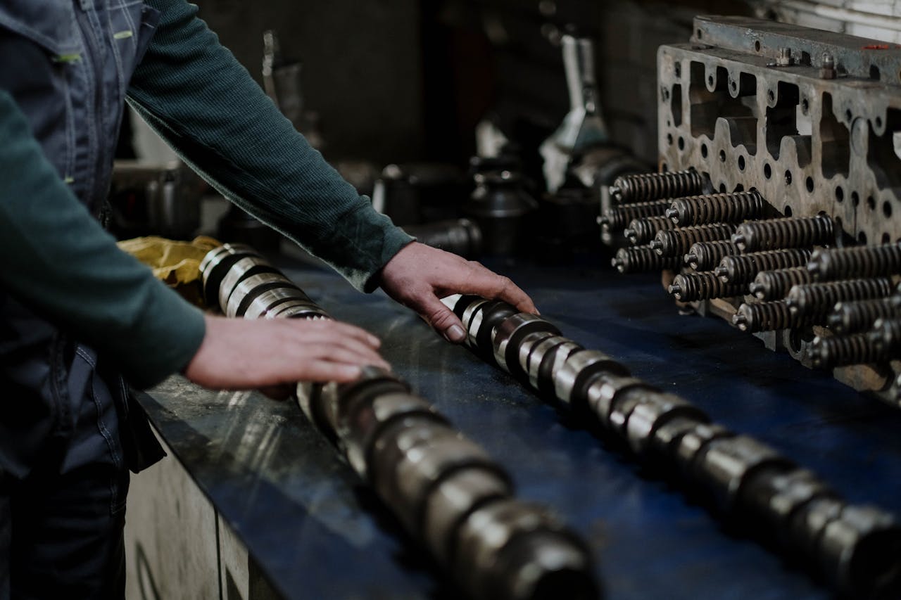 Services-03 Worker handling camshafts and cylinder head in a mechanic workshop.